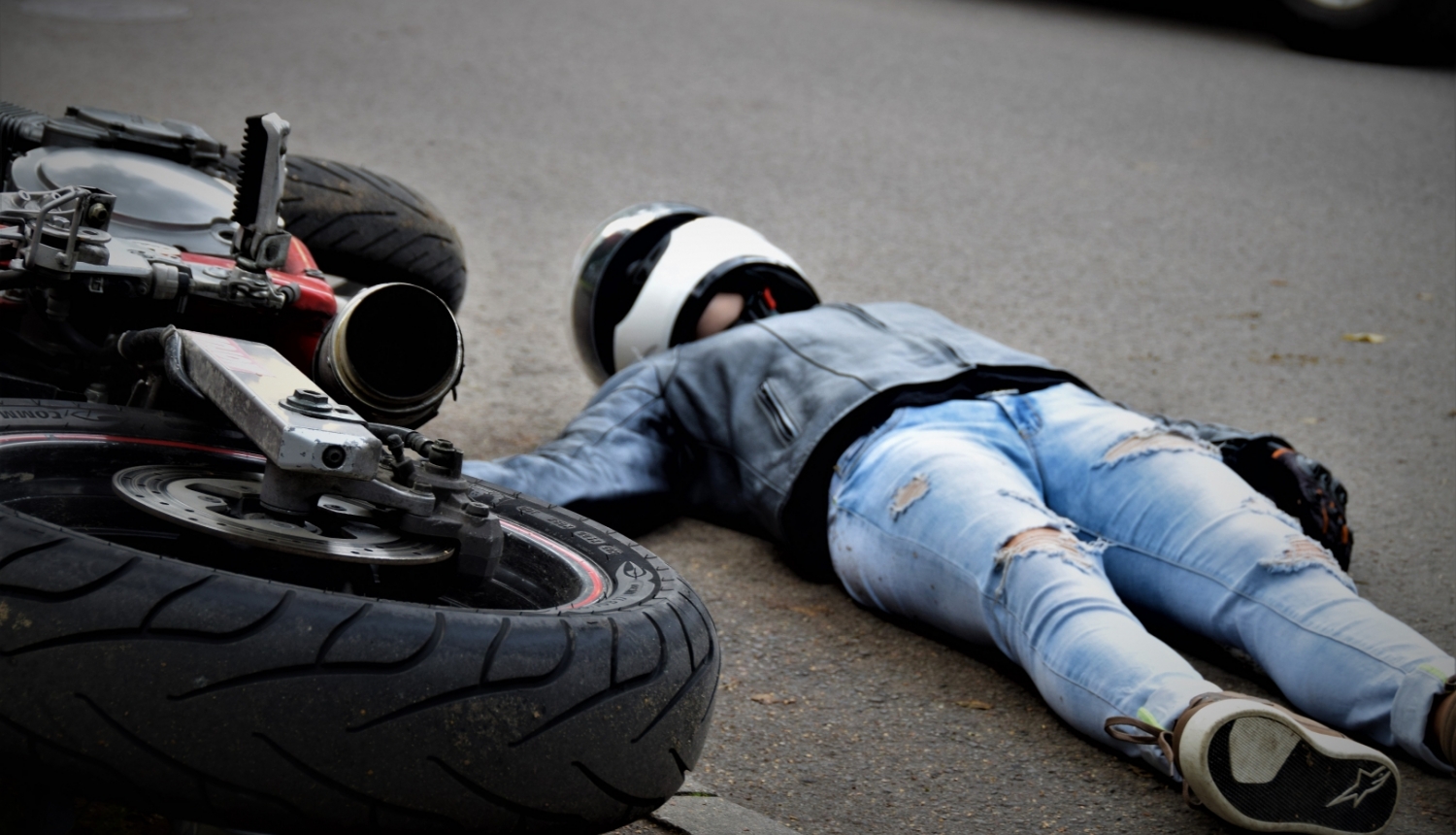 uz ielas apgāzies motocikls un motociklists guļ uz zemes (ilustratīva bilde)