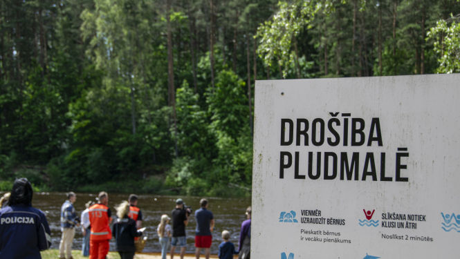Norāde - drošība pludmalē un fonā redzami cilvēki