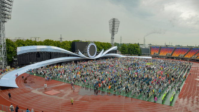 Daugavas stadionā pulcējas Dziesmu un deju svētku dalībnieki, apkārt nedaudz nomākušās debesis