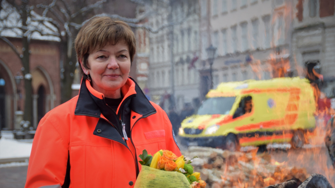 Dr. Dzintra Jakubaņeca stāv NMPD formā un fonā redzams operatīvais auto un ugunskurs