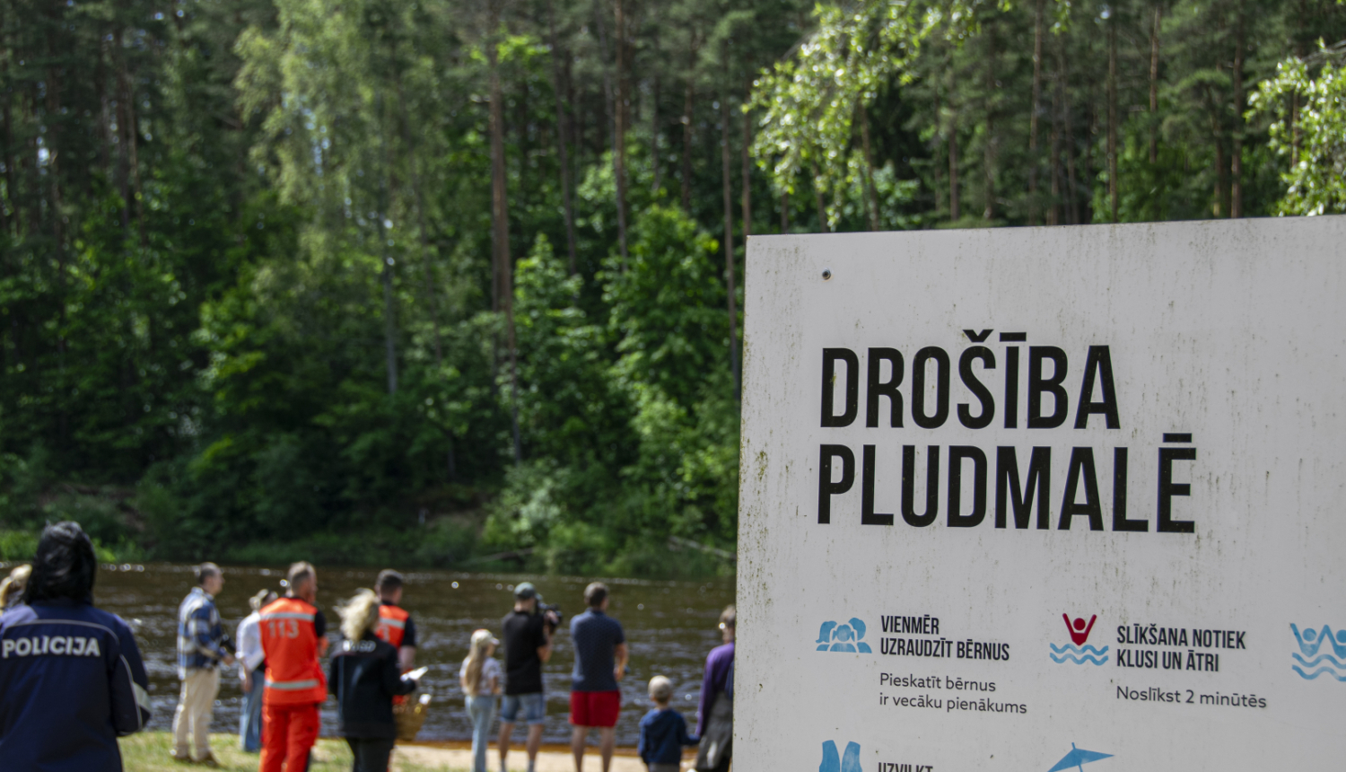 Norāde - drošība pludmalē un fonā redzami cilvēki