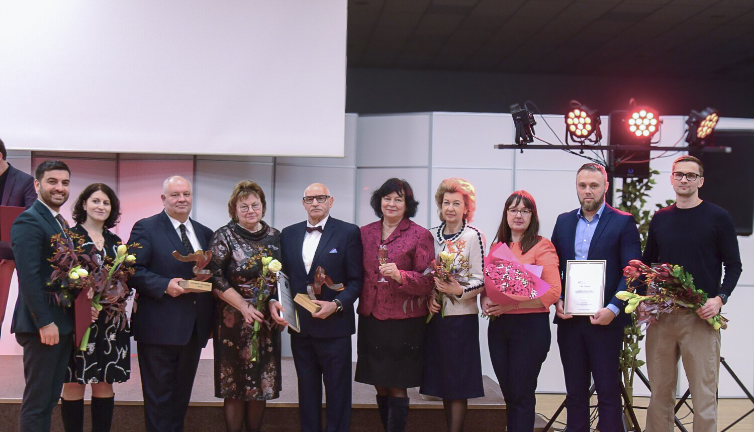 NM asociācijas apbalvojums, apbalvojuma saņēmēji ar ziediem stāv uz skatuves