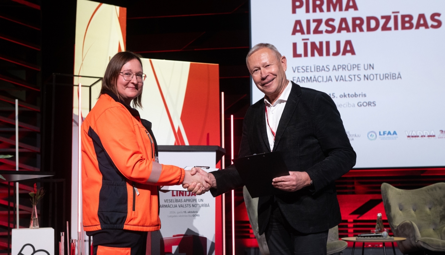 NMPD direktore un Veselības aprūpes darba devēju asociācijas valdes priekšēdētājs sarokojas pēc sadarbības līguma parakstīšanas