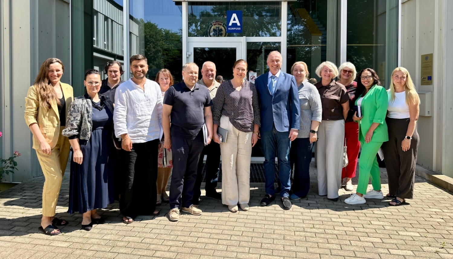 Speciālisti sastājušies kopbildē, fonā stikla durvis