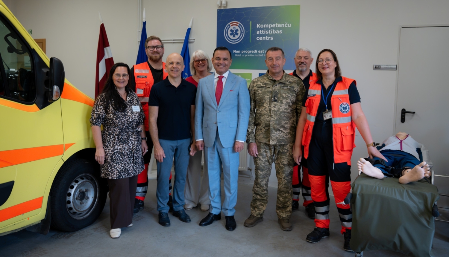 Vizītes pārstāvji sastājušies pie NMPD operatīvā auto un labajā pusē mācību manekens.