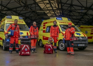 4 NMPD mediķi ar aprīkojumu stāv pie 2 operatīvajiem auto