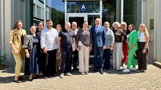 Speciālisti sastājušies kopbildē, fonā stikla durvis