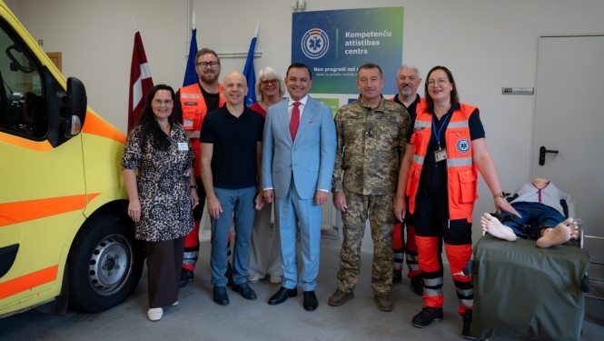 Vizītes pārstāvji sastājušies pie NMPD operatīvā auto un labajā pusē mācību manekens.