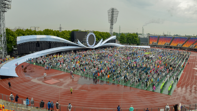 Daugavas stadionā pulcējas Dziesmu un deju svētku dalībnieki, apkārt nedaudz nomākušās debesis