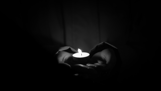 rokās tiek turēta aizdegta svecīte