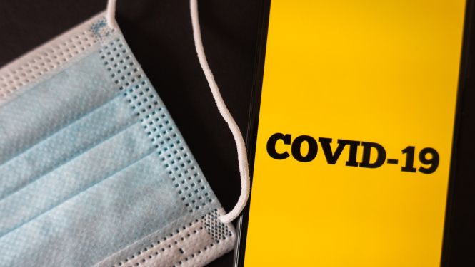 Covid-19 uzraksts telefonā un maska