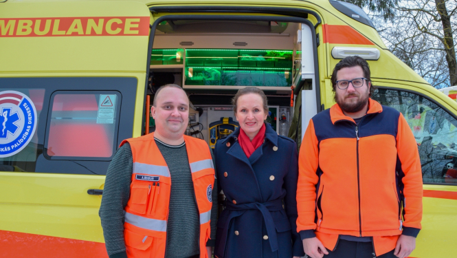 Veselības ministre vizītes laikā NMPD stāv pie operatīvā medicīniskā auto kopā ar diviem mediķiem