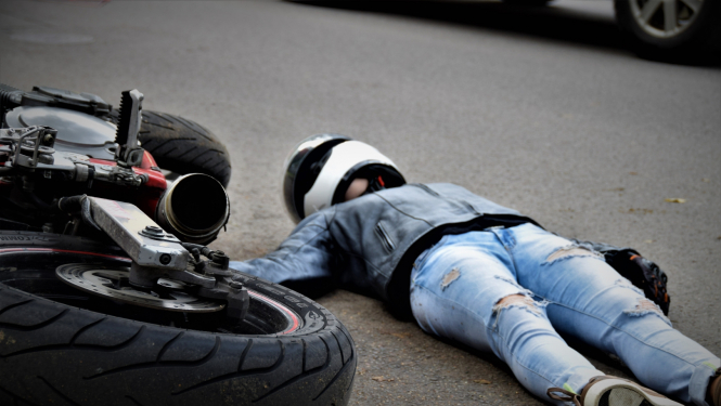 uz ielas apgāzies motocikls un motociklists guļ uz zemes (ilustratīva bilde)
