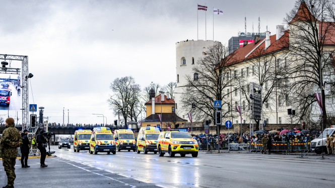 NMPD operatīvie auto brauc pa ielu, fonā prezidenta pils