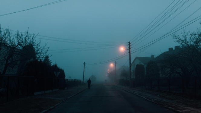 cilvēks tumsā iet pa ielu