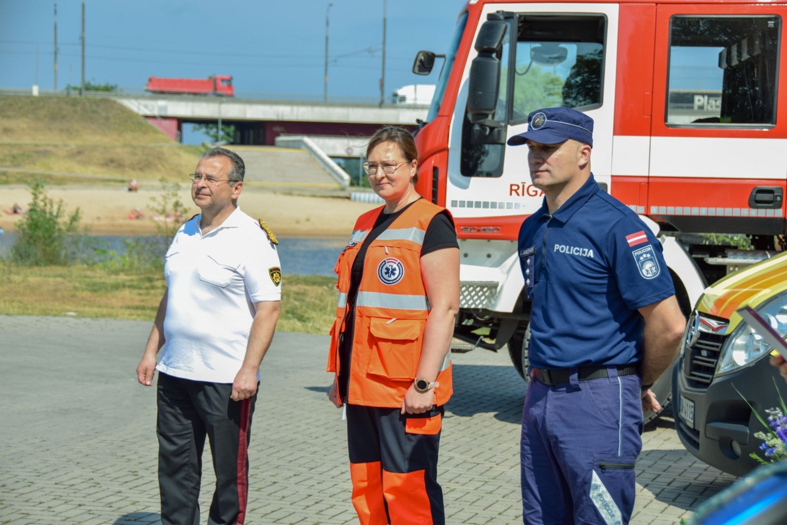 Operatīvo dienestu pārstāvji stāv pie operatīvajiem auto