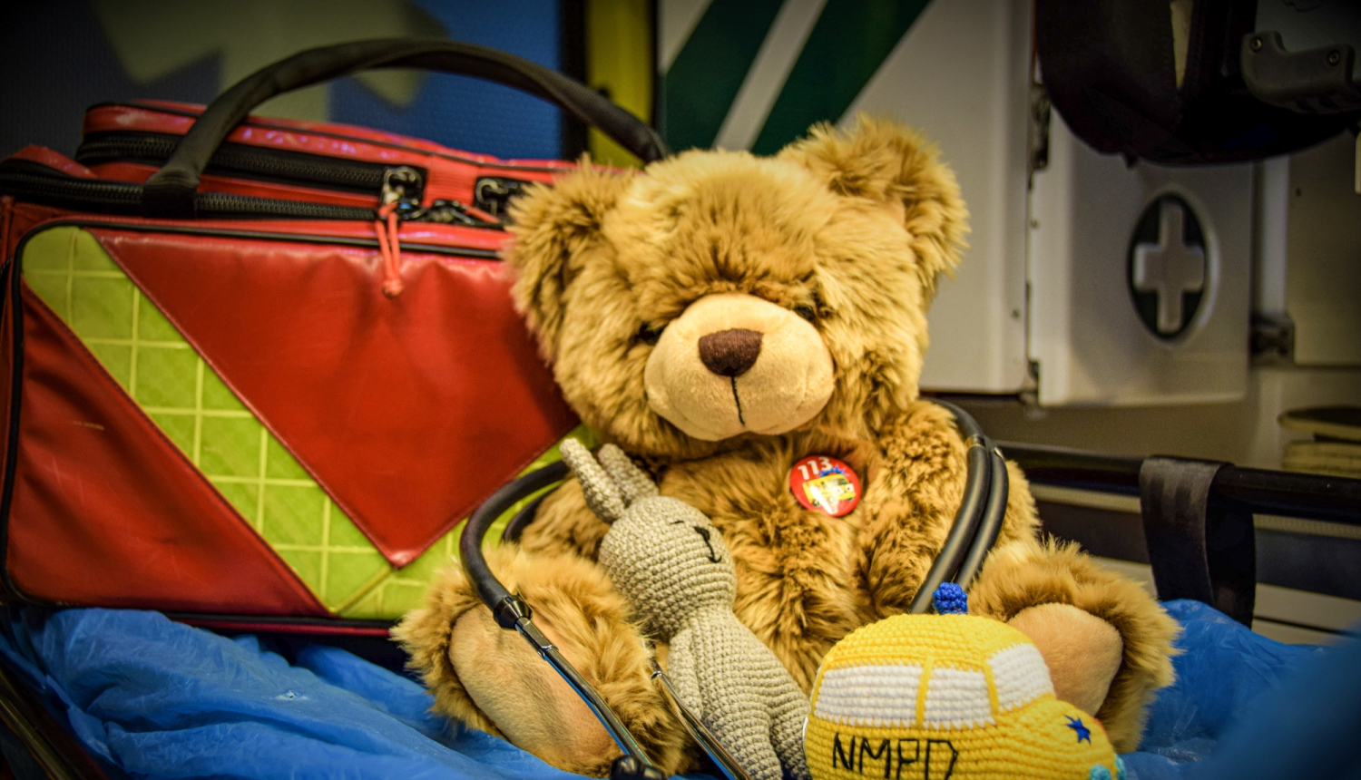 Rotaļu lācītis uz nestuvēm un tamborētu operatīvo medicīnisko auto