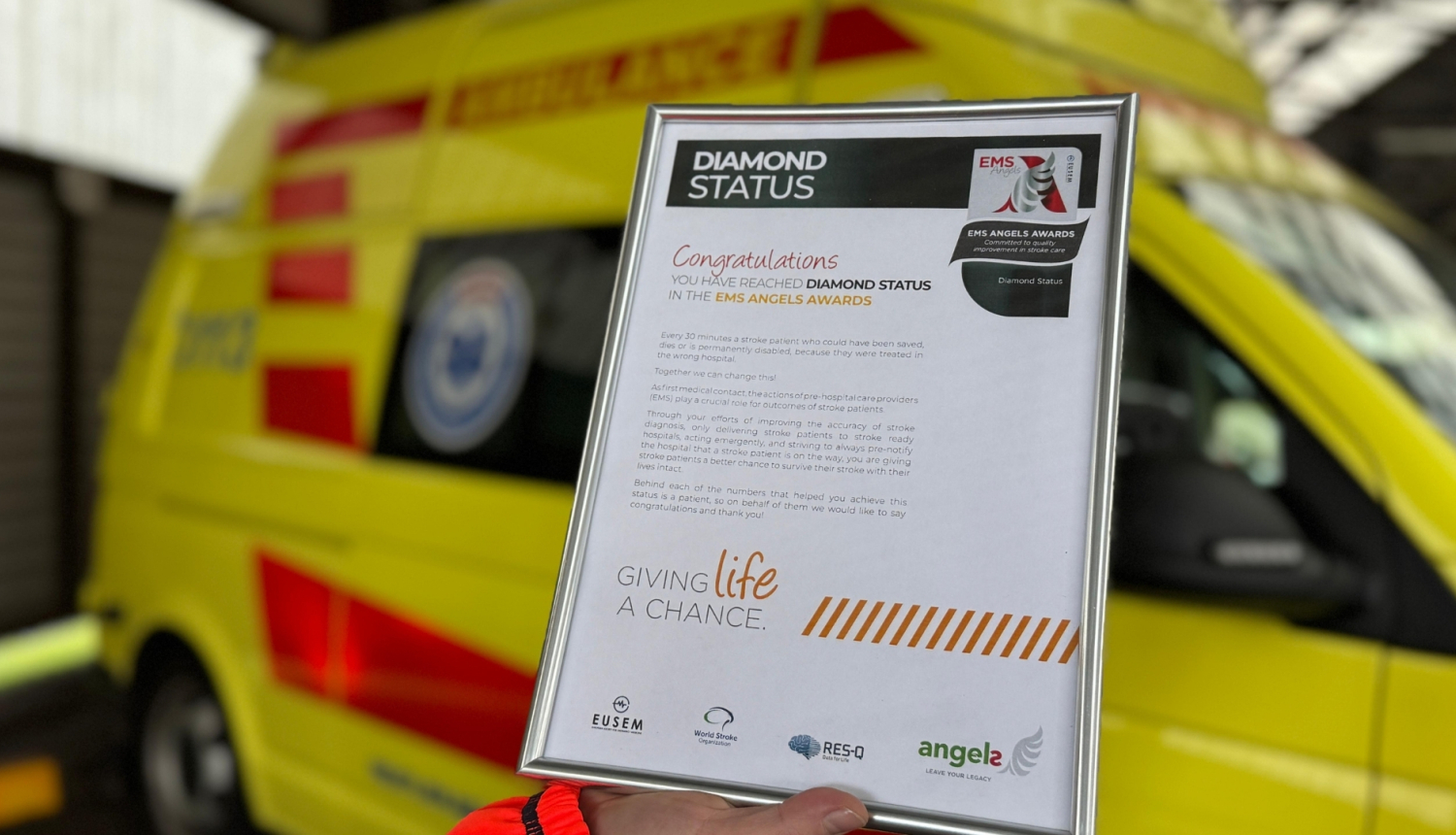 Eņģeļu iniciatīvas dimanta statusa apbalvojums piešķirts NMPD. Apbalvojumam fonā redzams NMPD operatīvais auto