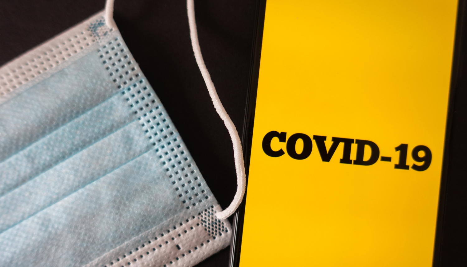 Covid-19 uzraksts telefonā un maska