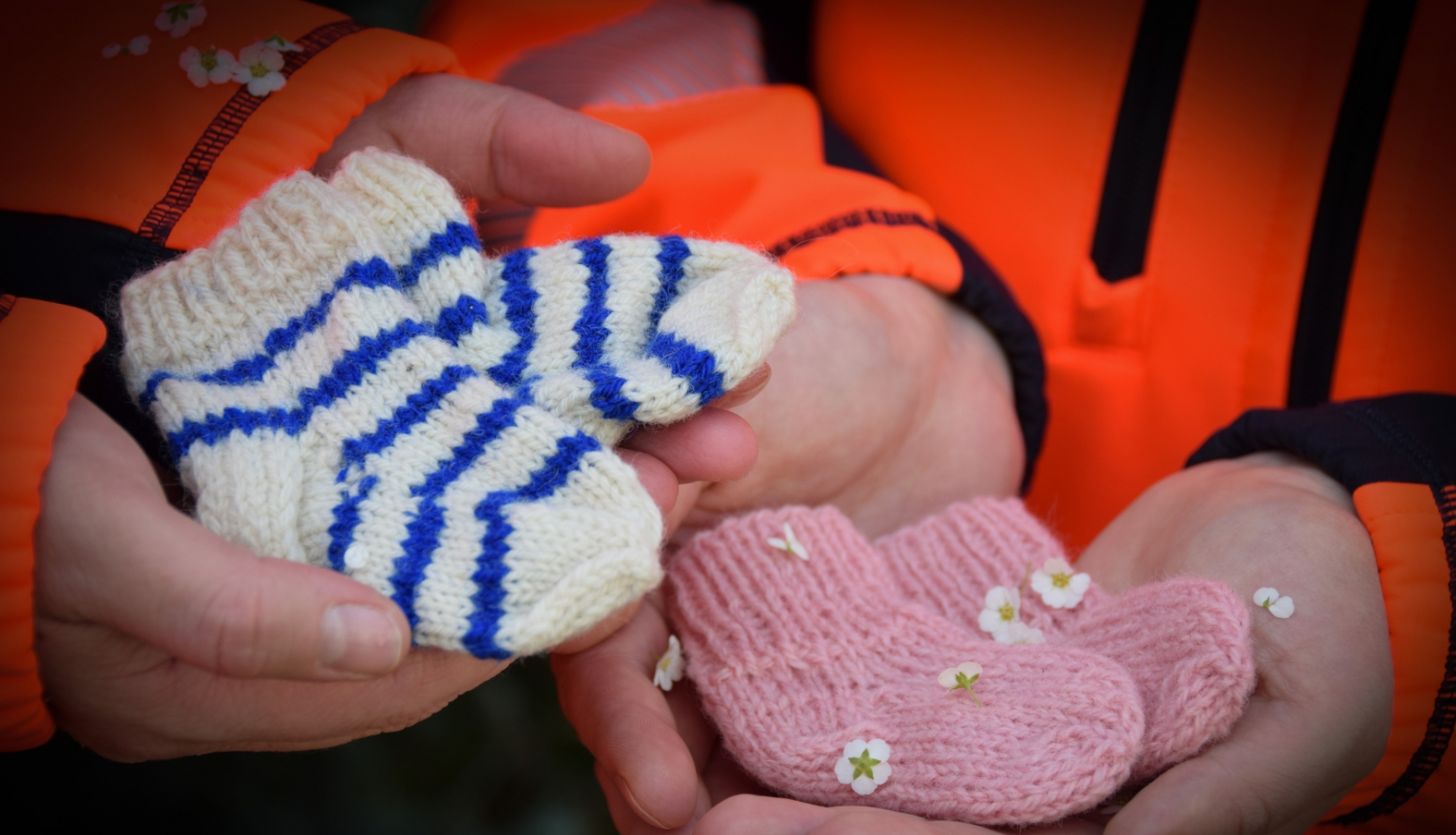 Divi mediķi rokās tur adītas zīdaiņu zeķītes rozā un zili/baltā krāsā