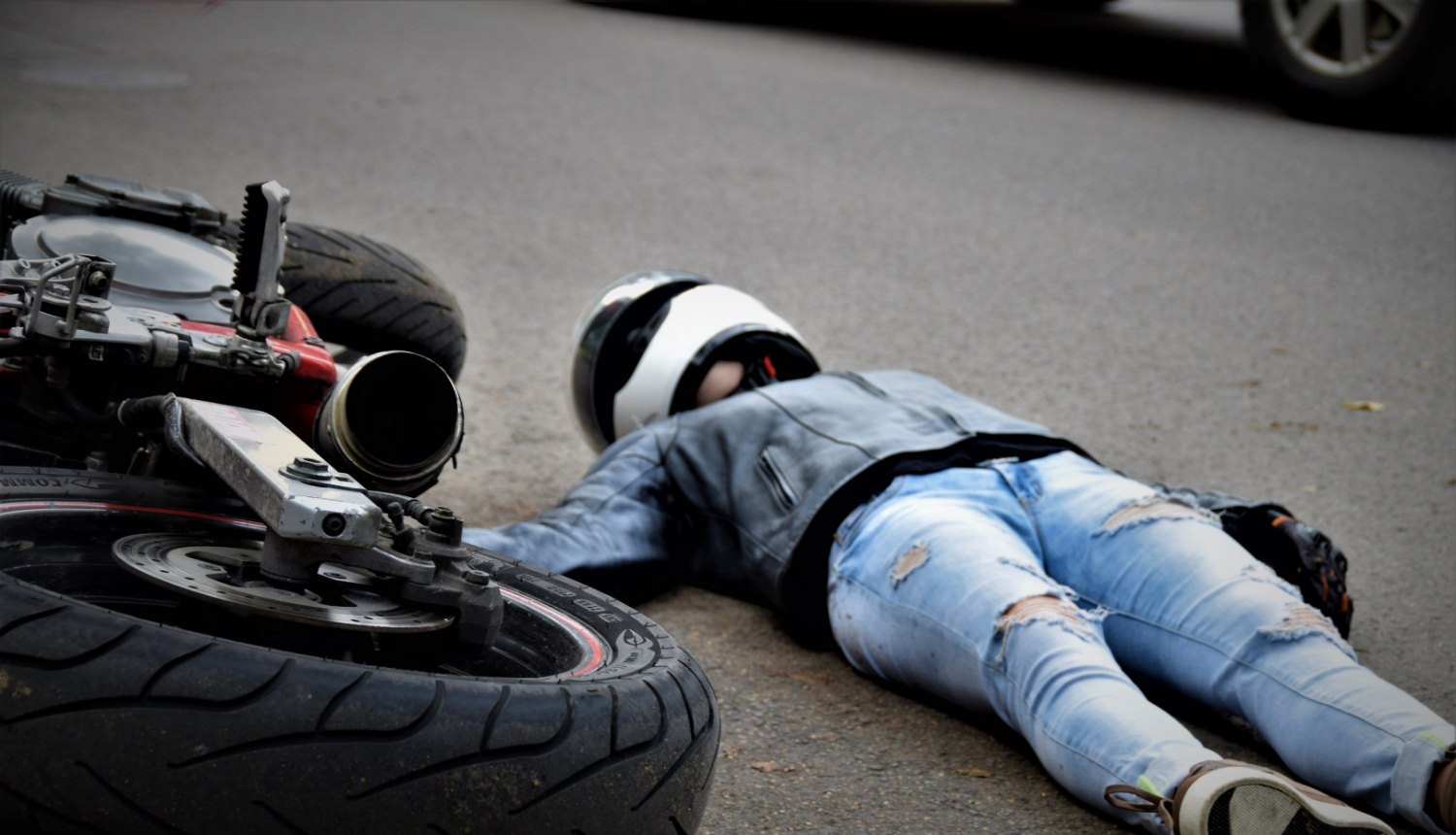 uz ielas apgāzies motocikls un motociklists guļ uz zemes (ilustratīva bilde)