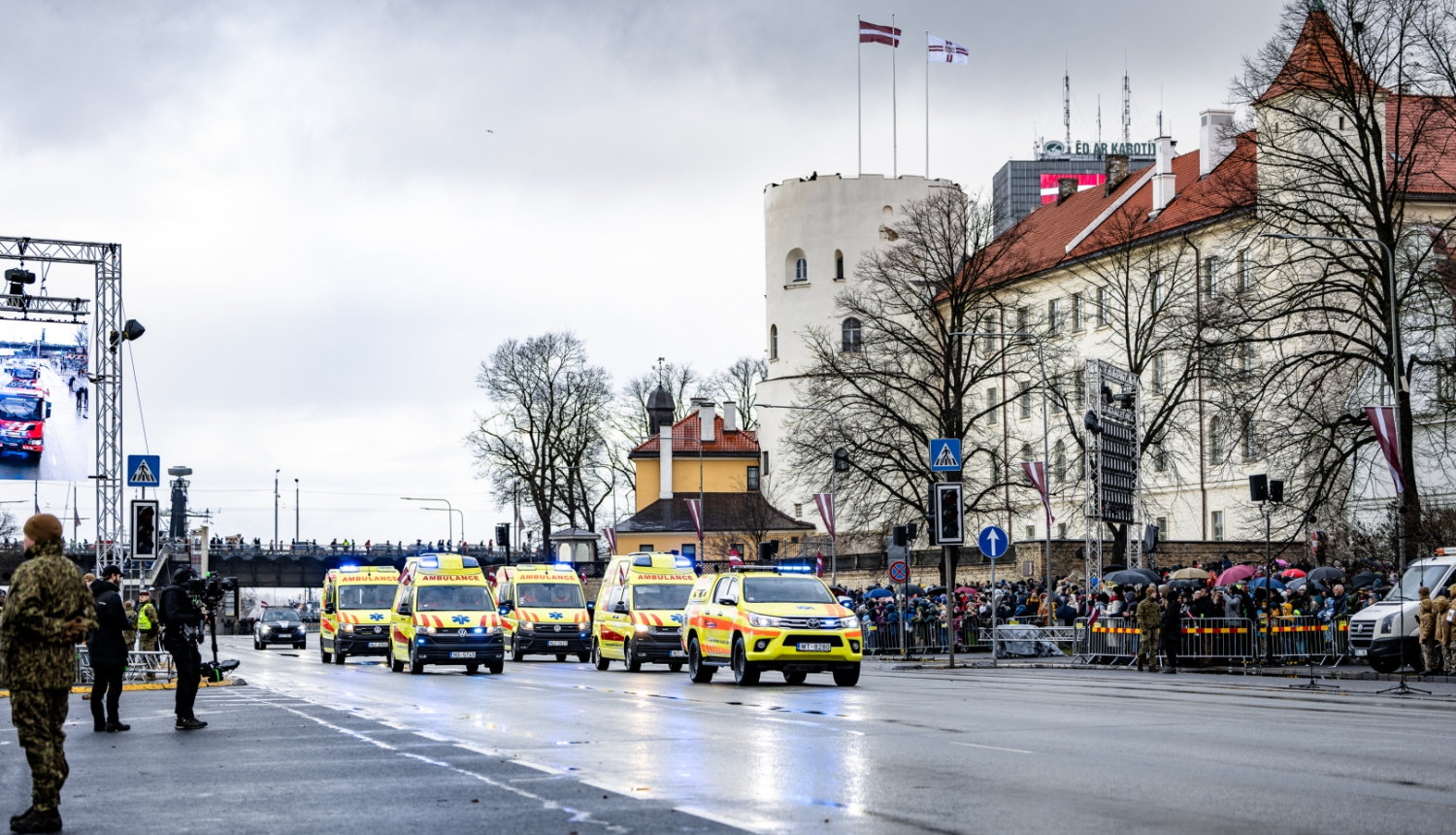 NMPD operatīvie auto brauc pa ielu, fonā prezidenta pils