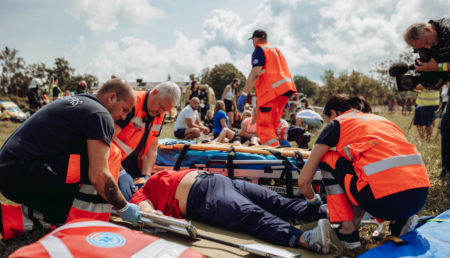 NMPD mediķi mācībās sniedz palīdzību. Apkārt 4 mediķi oranžās formās, priekšplānā soma