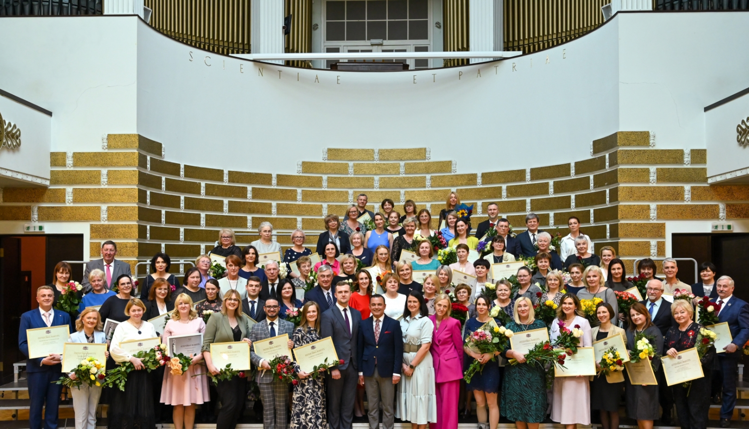 Cilvēki ar puķēm rokās stāv uz pakāpieniem