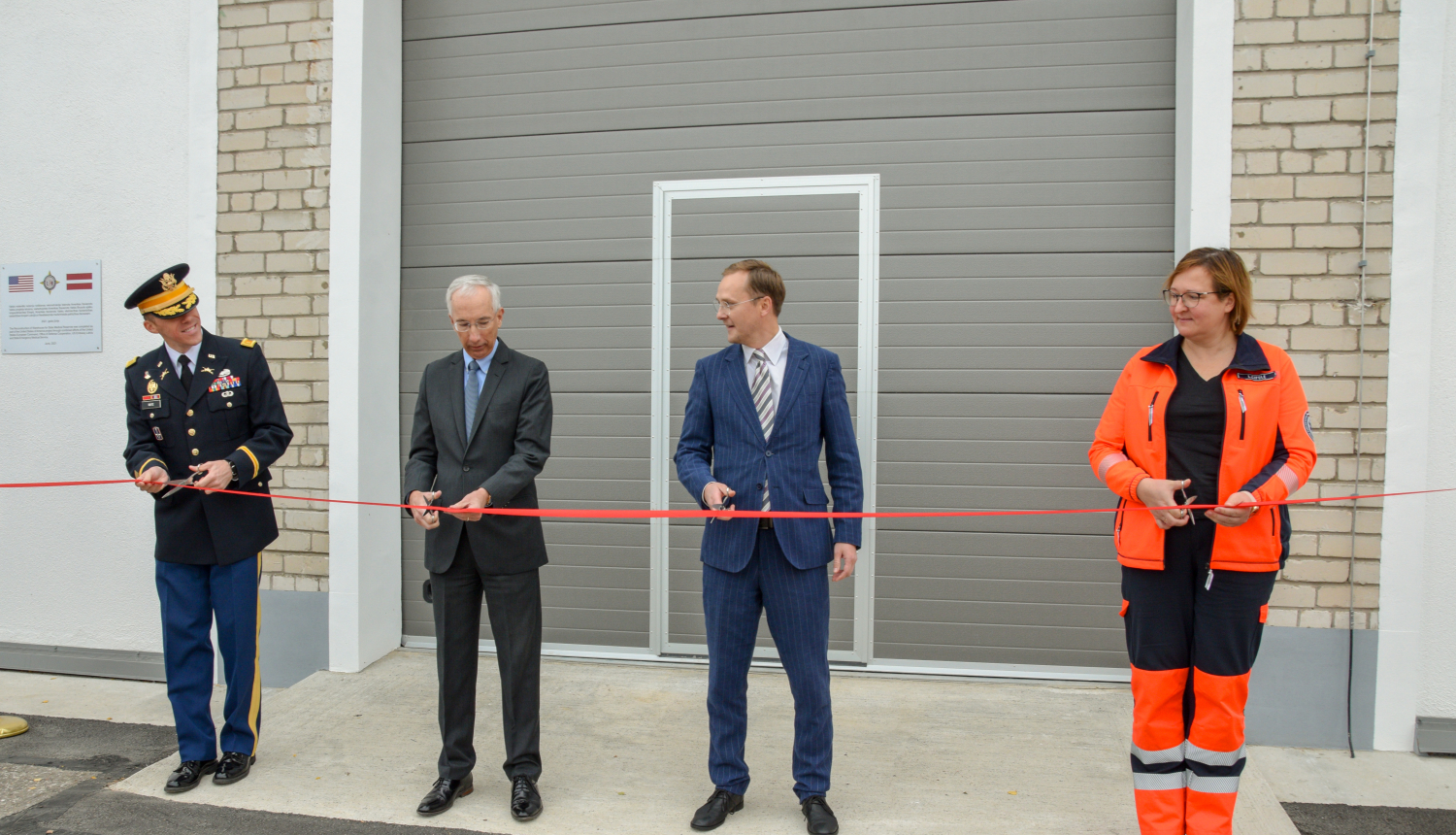 iestāžu pārstāvji griež lentīti, atklājot renovēto ēku